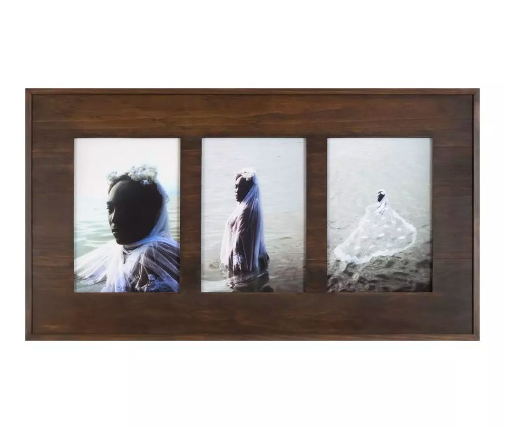 Três fotografias numa moldura de madeira: mulher negra de véu branco e coroa de flores no mar, cada vez mais distante.